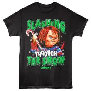 Spooky Chucky doll wearing holiday sweater holding candy cane on a black Christmas T-shirt with “Slashing Through the Snow” text.