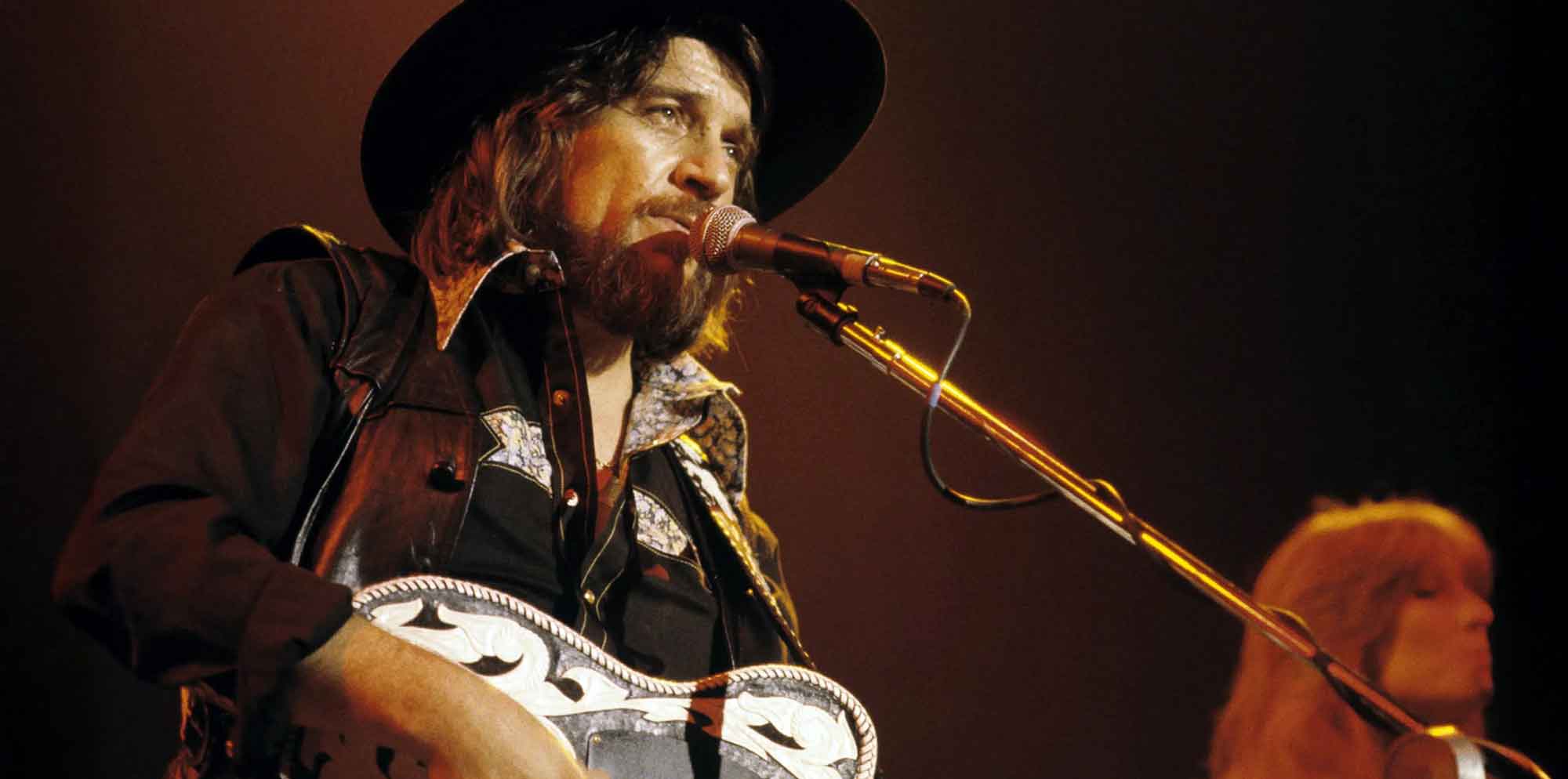 Iconic musician singing and playing guitar during live concert performance.