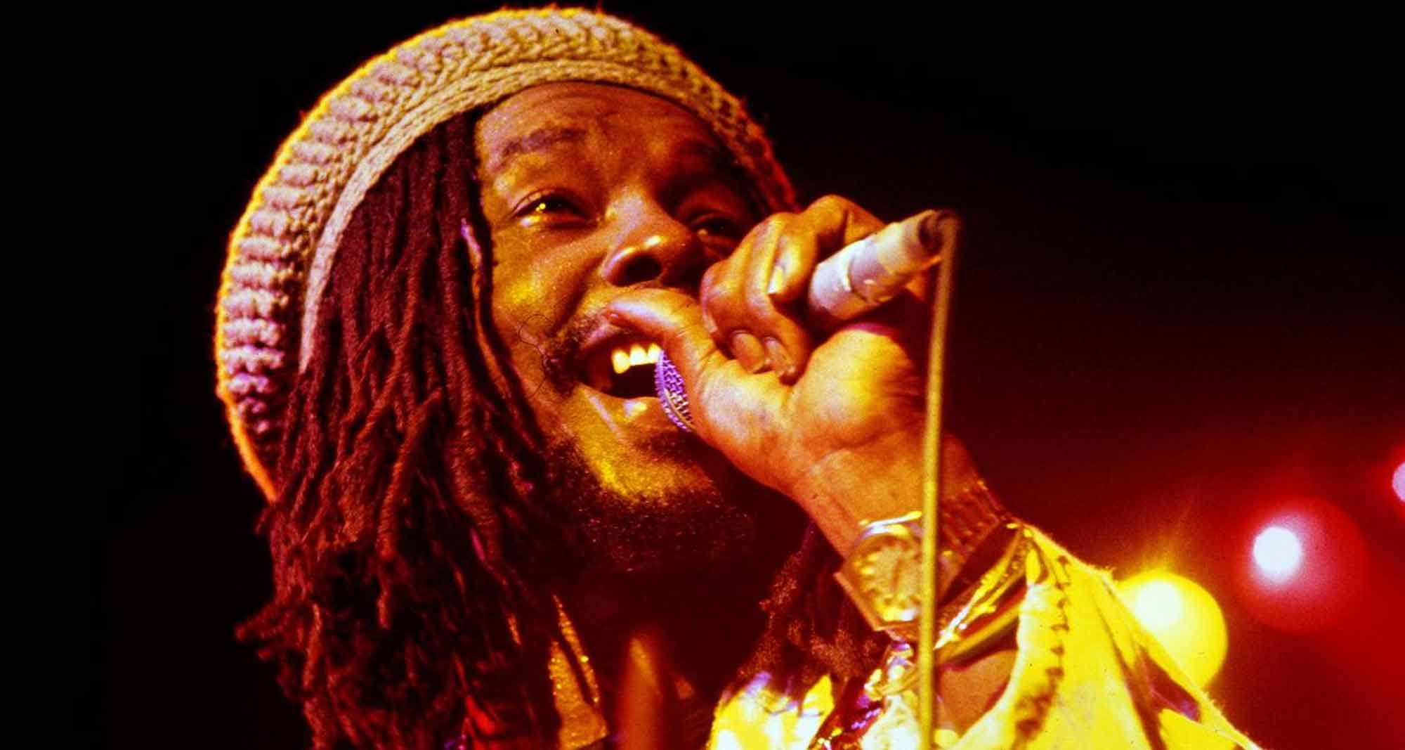 Rapper performing lively on stage with colorful lights and dynamic presence.