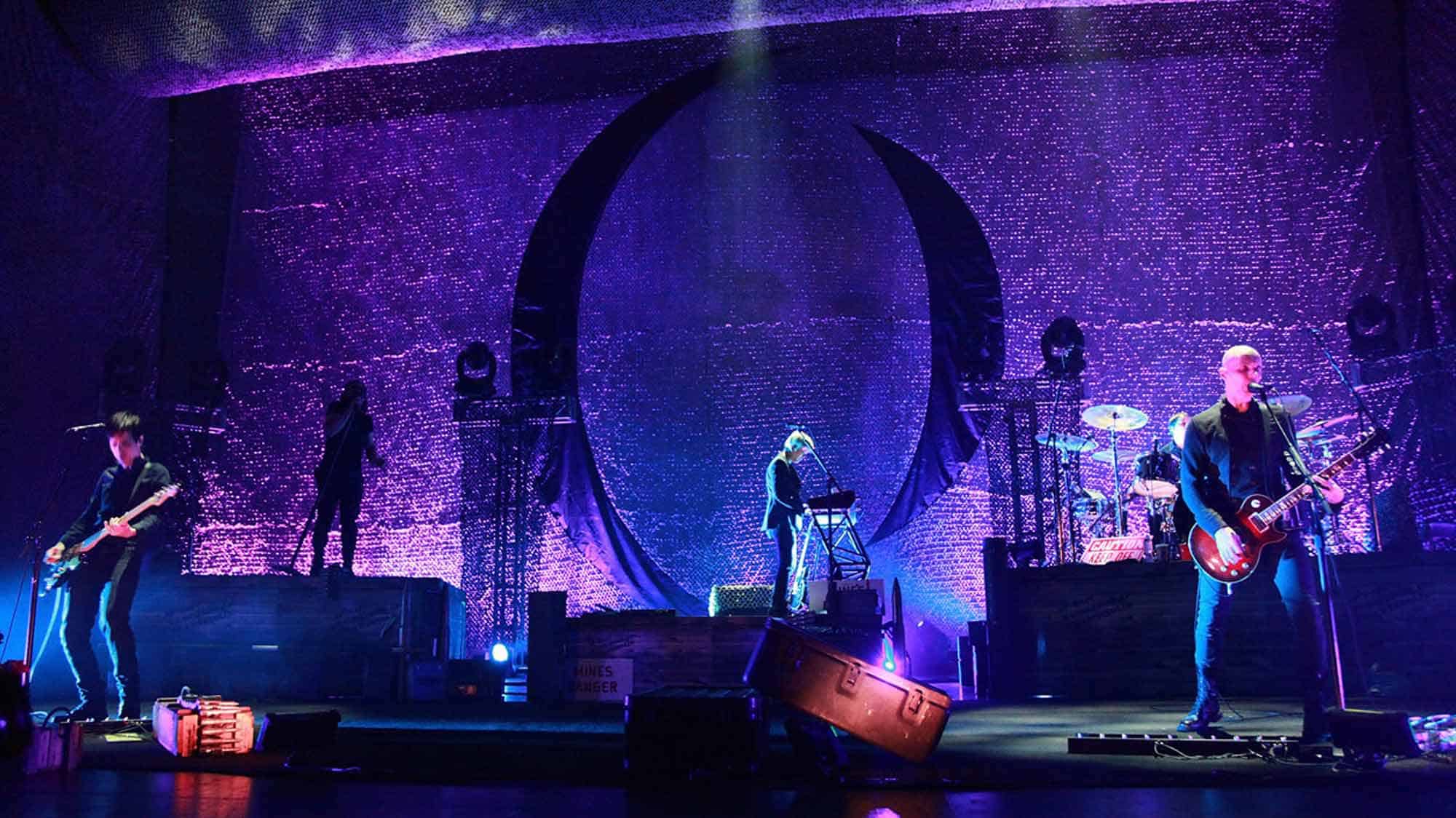 Colorful stage with musicians performing under purple LED lights, creating an energetic live music scene.