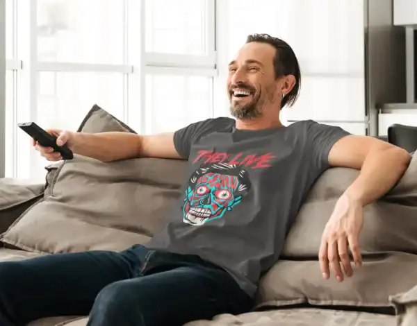 Smiling man in casual clothes relaxing on sofa, holding remote, enjoying leisure time at home.