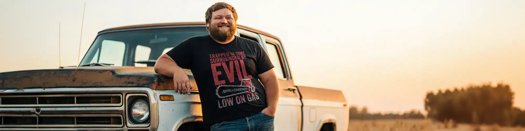 Casual man wearing "Evil Surrounded" graphic T-shirt outdoors.