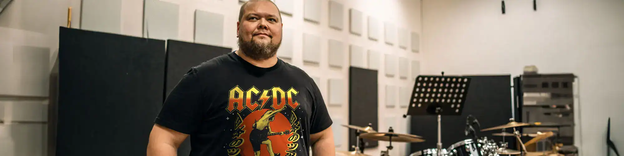 Music lover wearing AC/DC band t-shirt in professional recording studio environment.
