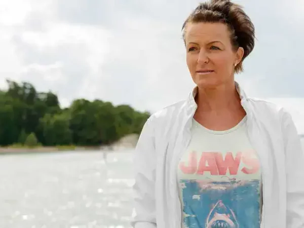 Woman wearing "Jaws" themed T-shirt outdoors on water.
